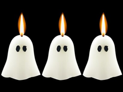 Three ghost-shaped candles with flames